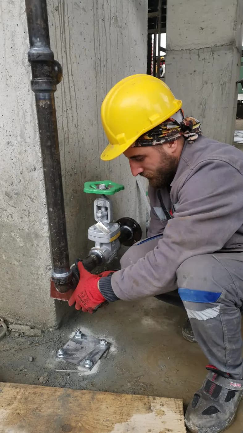 Monteur mit Helm bei Arbeiten an einer Armatur